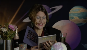 Frau liest Horoskop vor, im Hintergrund Weltall mit mehreren Planeten